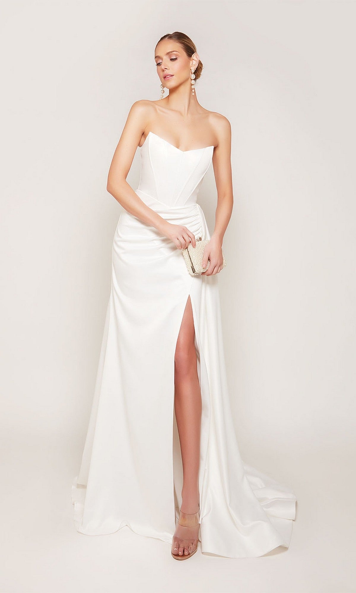 A woman models the Alyce 7093 long formal dress in diamond white—a strapless satin gown with a thigh-high slit—holding a clutch and posing against a plain background.
